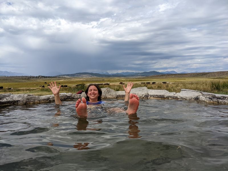 Photo of Rey floating in a hot spring tub with a big smile