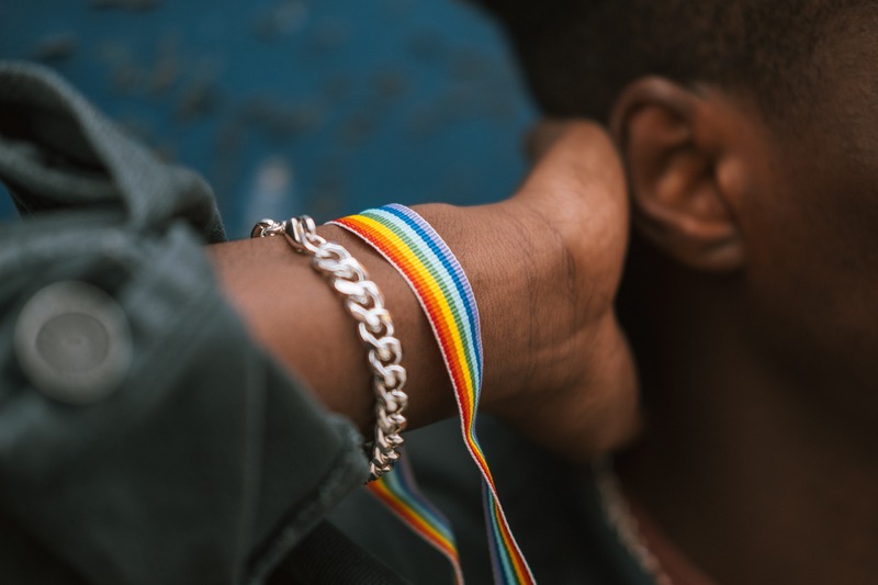 Close up of person's wrist wearing rainbow lanyard