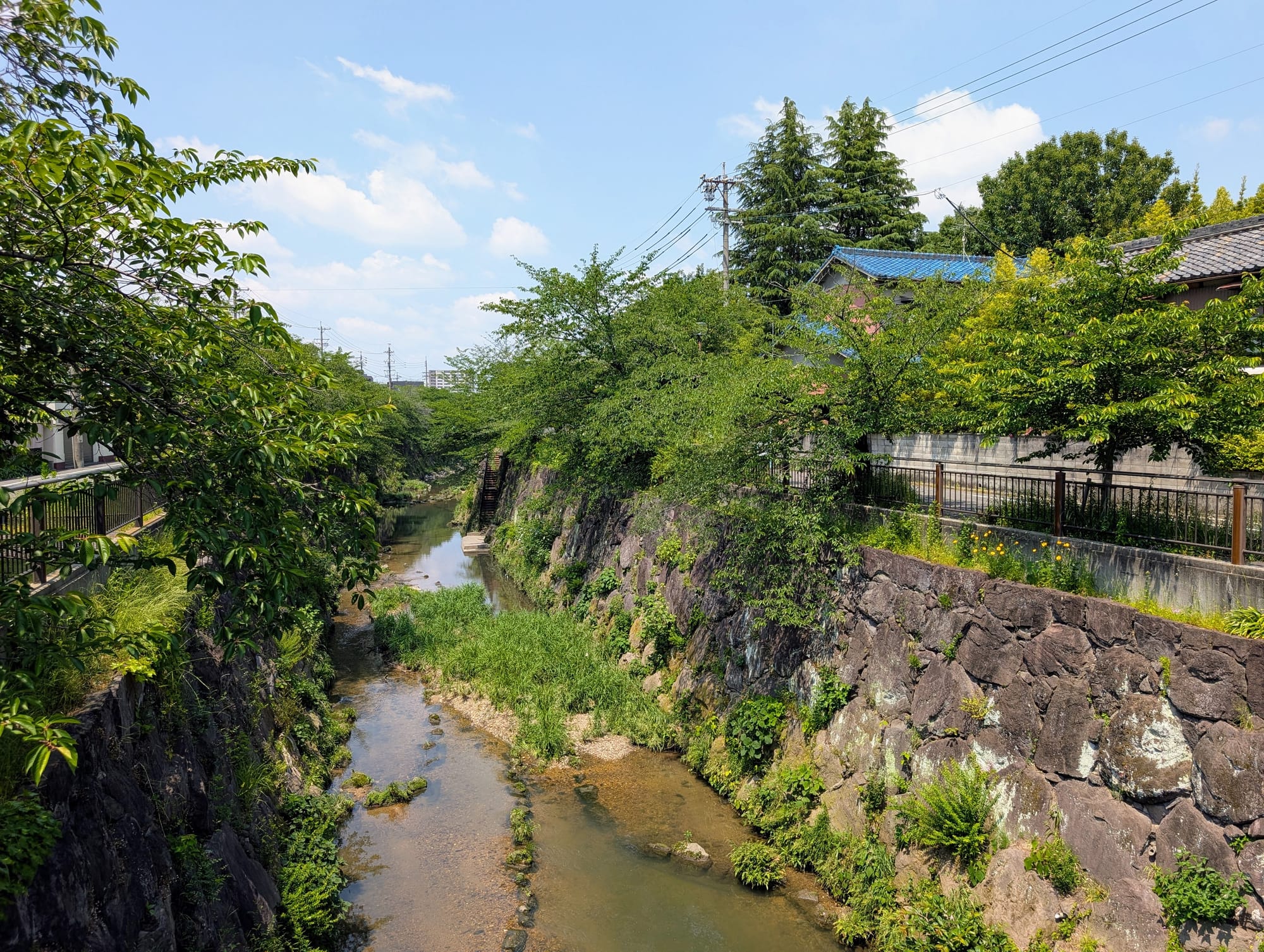 A river with high stone walls and trees on both sides winds through the city