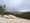 A granite dome in Tuolumne Meadows with trees and mountains in the background and a cloudy sky